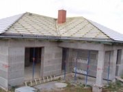 Ze šedé střechy stále trčí červený komín - stavební firma ještě neměla čas jej předělat