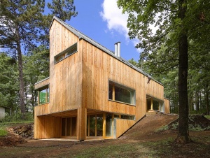 Dům, částečně zapuštěný do terénu, je zahalen do pláště z modřínových palubek. Architekti chtěli dát stavbě se sedlovou střechou kompaktní výraz, proto má střecha zaatikové okapní žlaby