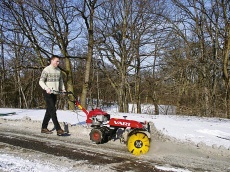 Odklízení sněhu z příjezdové cesty adaptérem rotačního kartáče k jednoosým traktorům Vari-Terra. Cena adaptéru činí podle typu až 20 000 Kč
