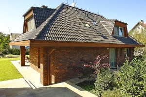 Osobitým znakem domů architekta Jiřího Houši je přesahující valbová střecha s výraznými lichoběžníkovými vikýři a obezdívka z režných cihel. Majitel domu vsadil na netradiční kombinaci barev a struktur terakotové cihly s plastickým povrchem a hladké stříbrné hliníkové okenní rámy vypadají na fasádě velmi dobře