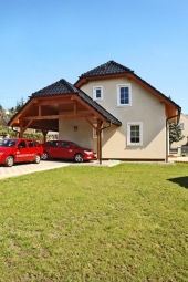 Snížená valbová střecha nad garážovým stáním přechází až ke vstupní partii domu a vytváří kryté závětří 