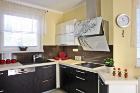 Kuchyňská linka vyrobená z MDF desek překvapí dynamickým moderním designem. Pozornost upoutá digestoř s dekorativními skleněnými prvky a tmavý velkoformátový obklad pracovní plochy