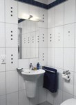  Ve spodní koupelně najdete jen jednoduché umyvadlo a závěsný klozet (VILLEROY & BOCH). Velkoformátové obklady (AGROB BUCHTAL) jsou doplněny listelami a inzerty se stříbrným a modrým čtvercovým vzorem. 
